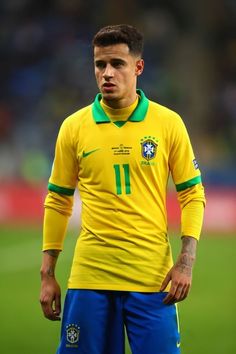 a soccer player in yellow and blue is standing on the field with his hand on his hip