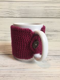 a knitted coffee cup cozys up with a button on the front and sides