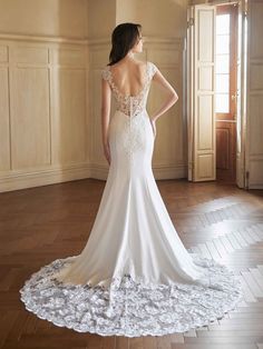 a woman in a wedding dress standing on a wooden floor with her back to the camera