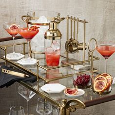 an assortment of cocktails and drinks on a glass table with gold accents, including grapefruit