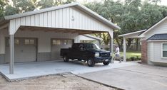 a black truck parked in front of a white building with a garage attached to it