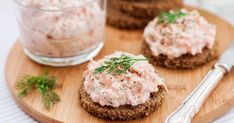 three crackers with crab salad on them are sitting on a cutting board next to a fork