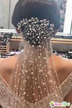 the back of a woman's head wearing a wedding veil with pearls on it