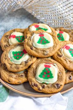 a plate full of cookies with white frosting and christmas tree decorations on them sitting on a table