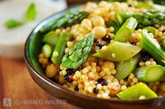 a bowl filled with corn and asparagus on top of a wooden table