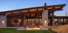 a modern house with a fire pit in the front yard at sunset or dawn time