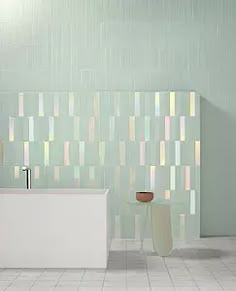 a white bath tub sitting in a bathroom next to a tiled wall covered in multicolored tiles