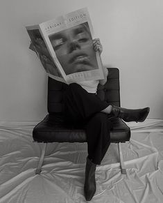 a person sitting in a chair with a magazine on their head and legs over their face