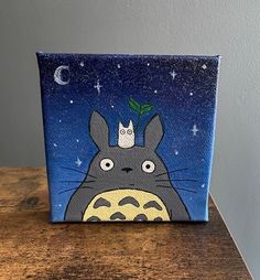 a painting of a totoro with a crown on it's head sitting on top of a wooden table