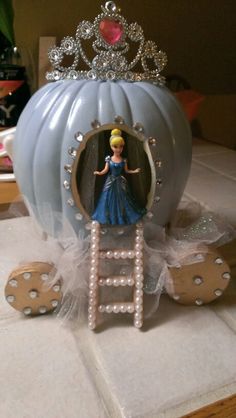 a blue carriage with a princess doll in the center and pearls on the sides, sitting on top of a table