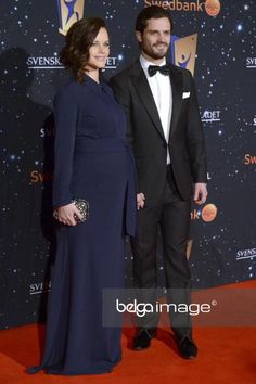 a man and woman in formal wear on the red carpet at an awards gala event