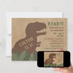 a person holding up a cell phone next to a card with an image of a dinosaur on it