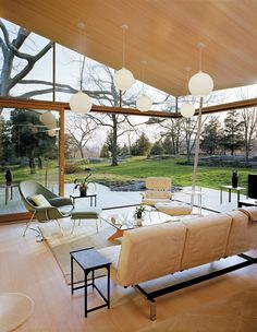 an open living room with glass walls and floor to ceiling windows that look out onto the backyard