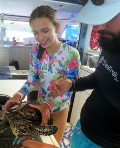 a man and woman are looking at a turtle