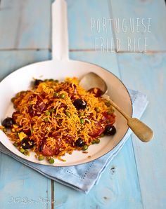 a white plate topped with lots of food on top of a blue wooden table next to a spoon