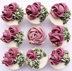 twelve cupcakes with pink frosting and green leaves on them, arranged in a circle