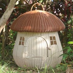 a white wicker house with a brown roof in the middle of some grass and trees