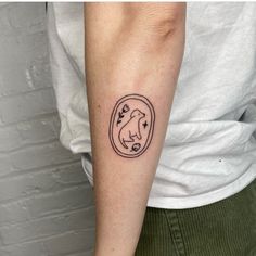 a woman's arm with a tattoo on it that has a dog in a circle