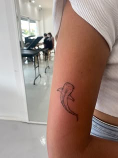 a woman's arm with a tattoo of a dolphin on the left side of her arm