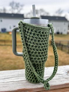 a crocheted coffee cup cozys up on a wooden table with a handle