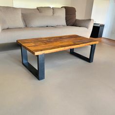 a wooden table sitting on top of a white floor next to a couch and coffee table