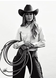 black and white photograph of a woman in cowboy attire holding a rope with her hands