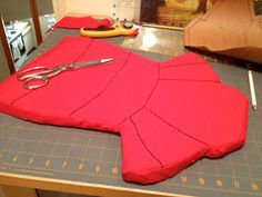 a pair of scissors sitting on top of a piece of red fabric next to a pair of scissors