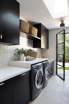 a washer and dryer in a room with black cabinets, white counter tops