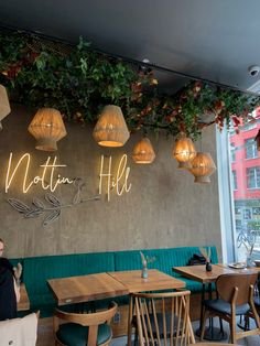 a woman sitting at a table in front of a wall with plants growing on it