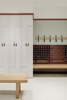 a wooden bench sitting in the middle of a room with white cabinets and tiled walls