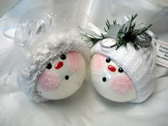 two white ornaments with red eyes and nose are sitting on a white cloth covered surface