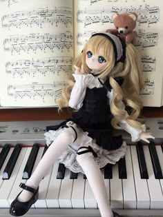 a doll sitting on top of a piano next to a teddy bear and sheet music