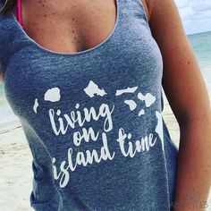 a woman standing on the beach wearing a tank top that says living on island time