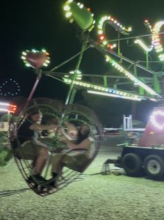 two people ride on a ferris wheel at the fairground with lights in the background