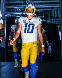 a football player is walking down the field with his helmet on and other players behind him