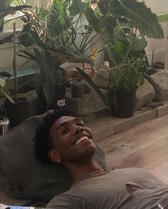 a man laying on the floor in front of some plants