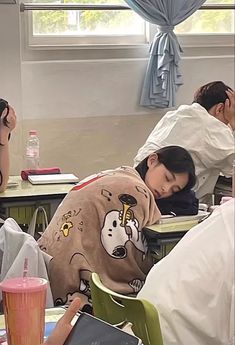 several people sleeping on desks in a classroom