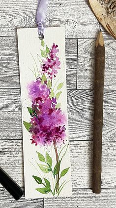 a piece of paper with watercolor flowers on it next to a pen and pencil