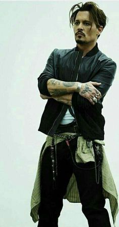 a man with tattoos and piercings standing in front of a white background wearing black pants