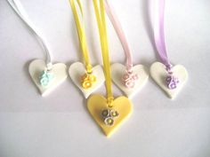 four heart shaped necklaces with bows and buttons on them are hanging from yellow cords