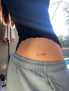 a woman's lower back with the word love tattooed on her left side ribcage