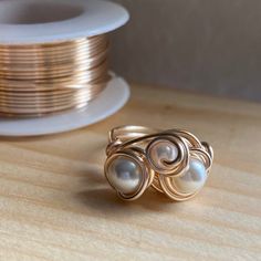 a close up of a ring on a table near some gold plates and a spool of thread