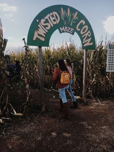 two people standing in front of a sign that says twisted corn maze on the side of a road