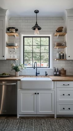 a white kitchen with open shelving and wooden counter tops, along with a dishwasher