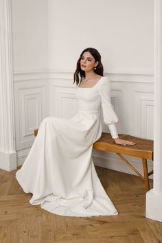 a woman is sitting on a bench in a white dress