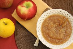 an apple and two apples on a placemat next to a bowl of peanut butter