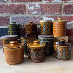 a group of ceramic containers sitting on top of a wooden table next to a brick wall