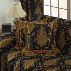 a blue and gold couch sitting in front of a window with a lamp on top of it