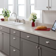 a tablet computer sitting on top of a kitchen counter next to a sink and window