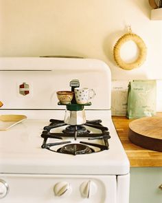 a white stove top oven sitting inside of a kitchen next to a wooden cutting board